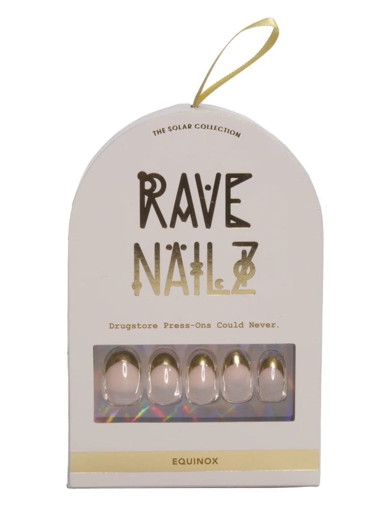 Rave Nailz Equinox press-on nail kit in white arched box with gold foil branding, showing five blush pink oval nails with gold French tips